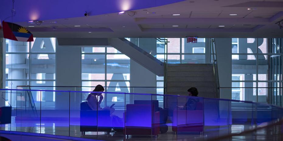 Business students studying together in a blue-lit lobby space