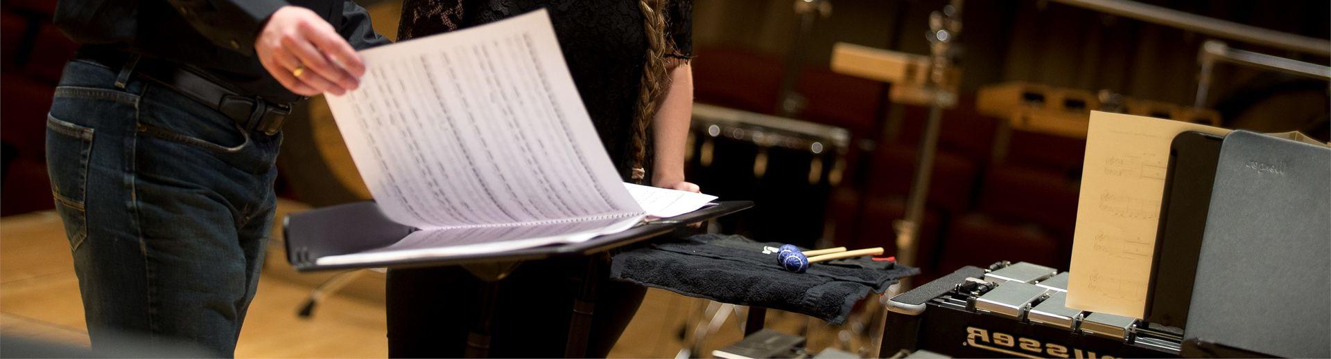 A student and professor look at sheet music together.