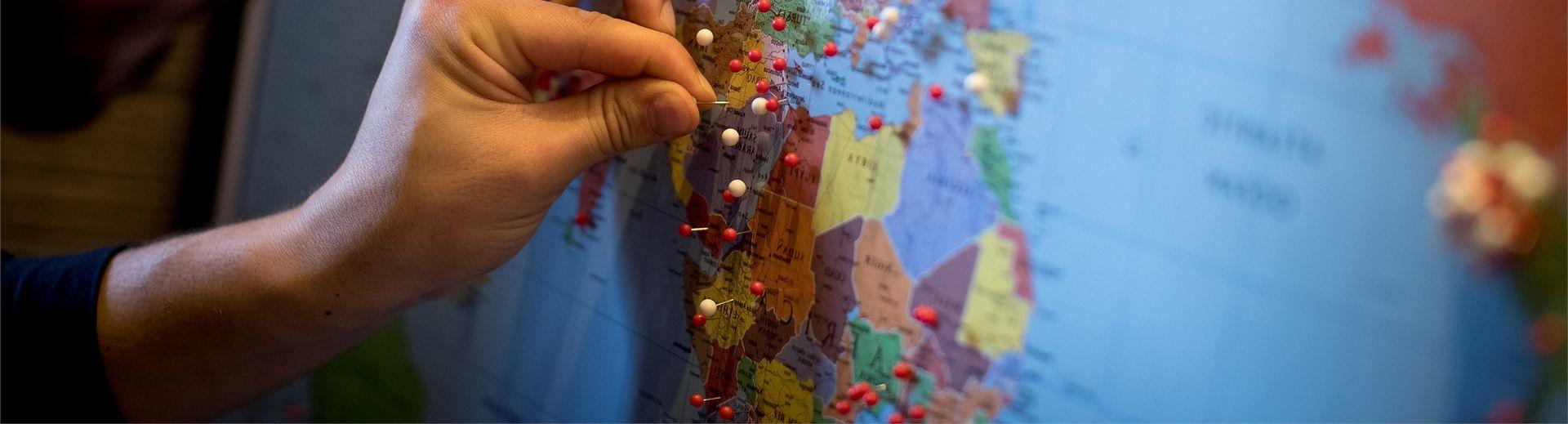 A man placing a pin in a world map. 