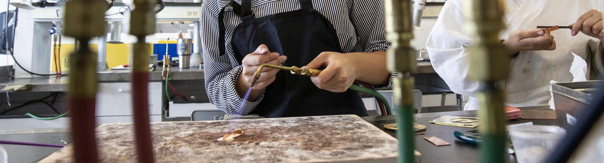 A student wearing safety glasses is working with a torch in Tyler's 金属 studio.