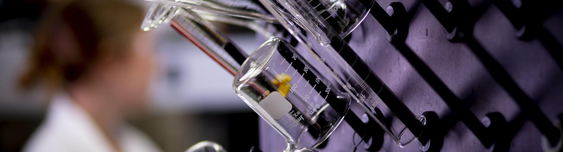 Research student in a lab at Temple in the College of Science and Technology with beakers and test tubes.