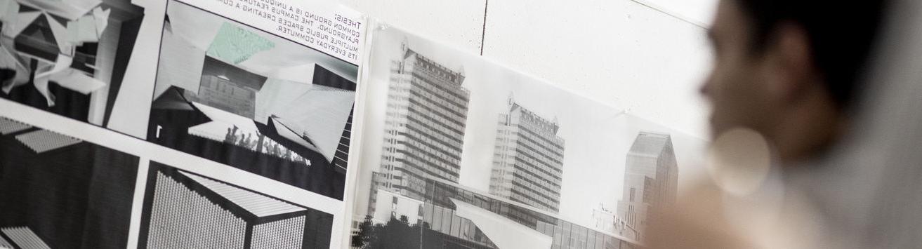 Black and white architectural renderings appear on a wall as a blurred figure looks on.