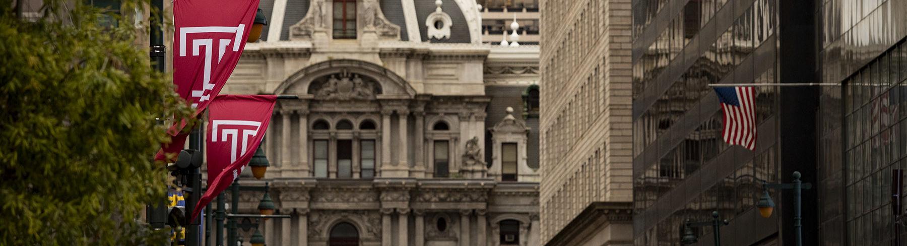 Philadelphia's City Hall building on Market Street lined with cherry red Temple T flags