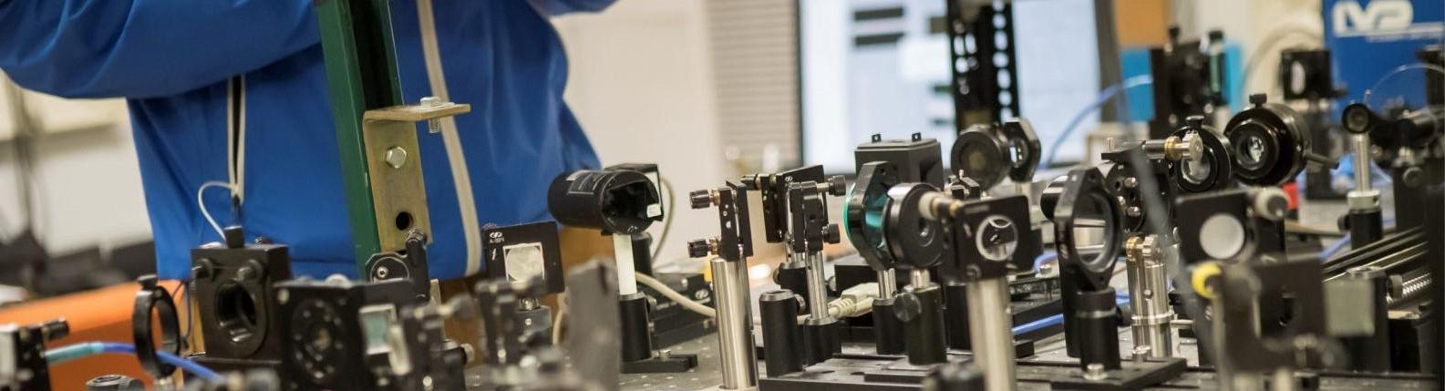 Temple student standing over table of equipment in a College of Science and Technology facility.