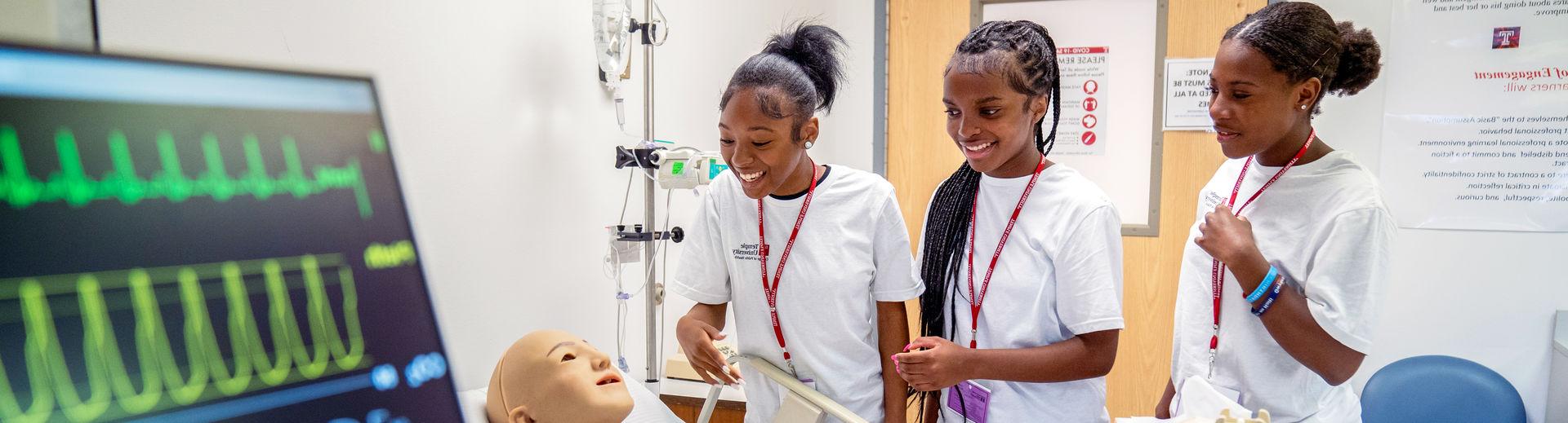 Three Nursing program students working on a simulated patient in the lab