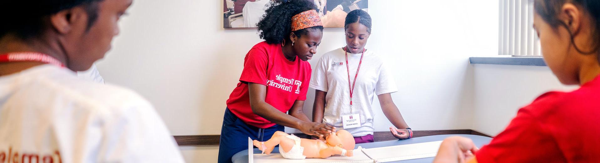 Two nursing students working with a simulated infant patient in the lab