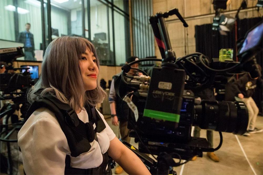 A film student sitting among film equipment in a film studio on campus.