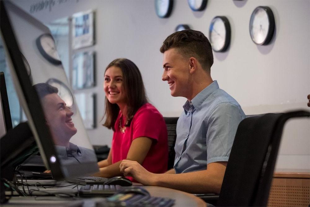 Fox students discuss homework while working at a computer station.